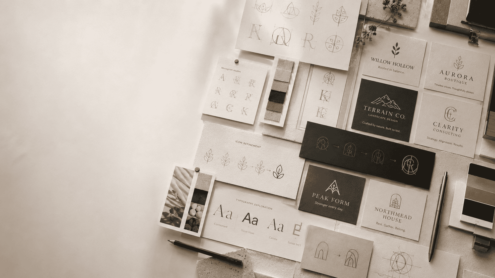 Minimal branding workspace showing logo sketches, typography studies, color swatches, and refined logo and tagline concepts laid out on a design table.